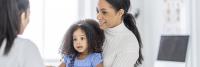 Mother and child listen to doctor during office visit.